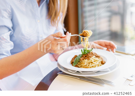 Young happy woman sitting at the table in cafe and enjoying the meal. Hungry woman eating tasty 41252465