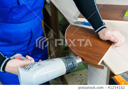 Professional carpenter at work dries a tree by a professional industrial hair dryer hand tool close 41254182