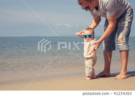 Father and baby son playing on the beach at the day time. Father and baby son playing on the beach at the day time. 41254263
