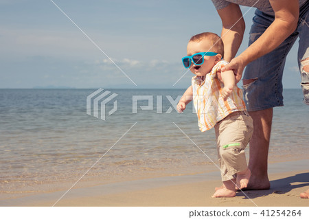 Father and baby son playing on the beach at the day time. Father and baby son playing on the beach at the day time. 41254264