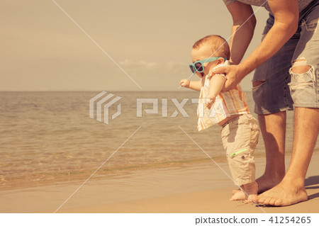 Father and baby son playing on the beach at the day time. Father and baby son playing on the beach at the day time. 41254265