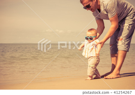 Father and baby son playing on the beach at the day time. Father and baby son playing on the beach at the day time. 41254267