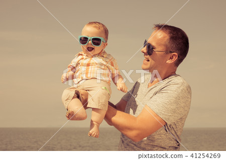 Father and baby son playing on the beach at the day time. Father and baby son playing on the beach at the day time. 41254269