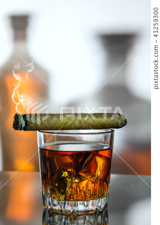 A glass of whiskey and a smoke cigar A glass of whiskey and a smoke cigar 41259300