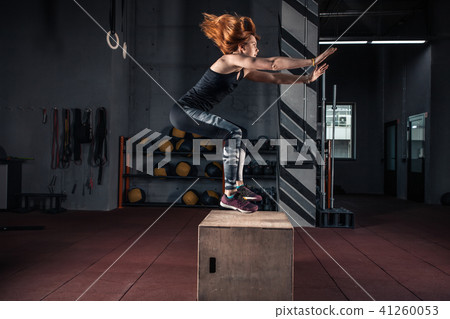 Sporty girl jumping over some boxes in a gym Sporty girl jumping over some boxes in a gym 41260053