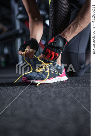 Beautiful woman tying shoelaces at gym Beautiful woman tying shoelaces at gym 41260211