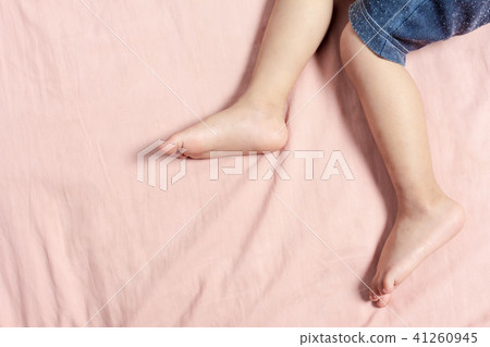The Baby Boy Legs lie on the pink mattress. 41260945
