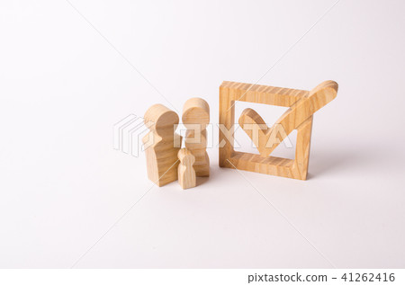 Wooden figures of people stand near the tick Wooden figures of people stand near the tick 41262416