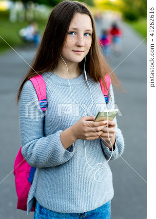 Beautiful girl brunette schoolgirl. Summer in nature. Behind back is pink backpack. In hands of 41262616