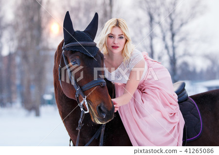 Young woman in dress riding horse on winter field 41265086
