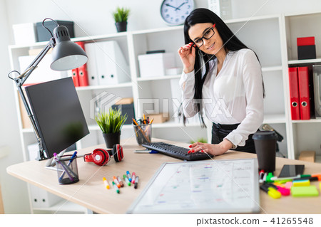 A young girl stands near a table and prints on the keyboard. Before the girl is a magnetic board and 41265548