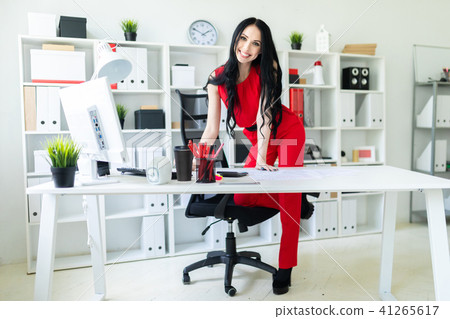 A beautiful young girl stands near an office desk, putting her foot on a chair. A beautiful young girl stands near an office desk, putting her foot on a chair. 41265617