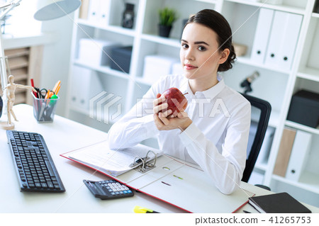 Young girl in the office working with documents and holding an apple. 41265753