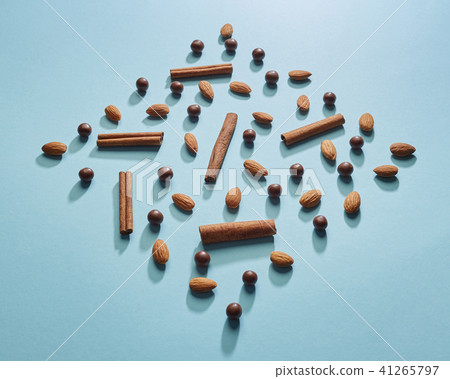 Chocolate balls, almonds, cinnamon in the shape of a diamond on a blue paper background. Flat lay 41265797