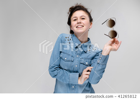 Young brunette girl holding glasses in her hand. Cat glasses. The hair is gathered in a bun. 41265812