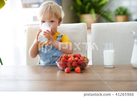 happy baby boy eating strawberries with milk 41265988