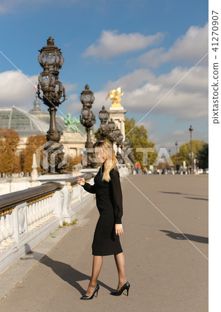 Young woman walking near street vintage lights and white concrete railing in France. Young woman walking near street vintage lights and white concrete railing in France. 41270907