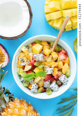 Healthy fruit salad with mango, pineapple, peach and pitaya on bright blue background 41274444