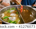 Freshly sliced meat with chopsticks over hot pot 41276073