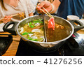 Sliced pork meat with chopsticks over hot pot 41276256