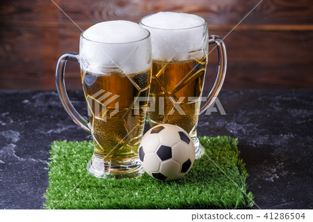 Image of two glasses of beer, soccer ball on green grass 41286504
