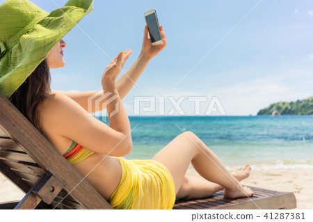 Attractive young woman sending a love message through a selfie on the beach Attractive young woman sending a love message through a selfie on the beach 41287381
