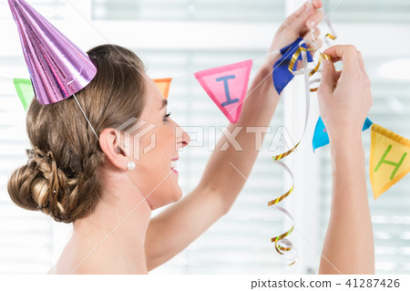 Happy adult woman hanging decorations for her birthday party 41287426