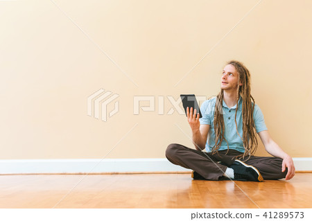 Young man using his tablet on in a large room 41289573