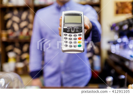Photo of male retailer with terminal for bank card in hands. 41291105