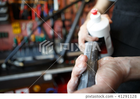 Photo of man cleaning part of bicycle against rust. Photo of man cleaning part of bicycle against rust. 41291128