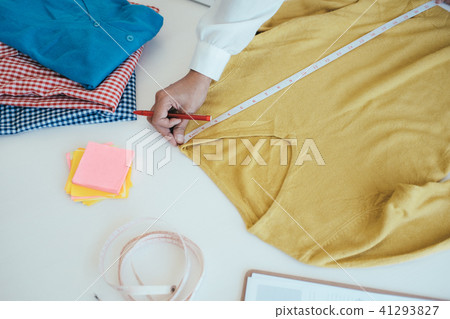 Designer measuring the long sleeve shirt. 41293827