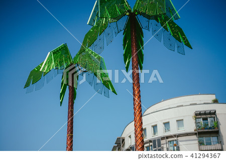 Artificial green metal palms with white living house and blue sky background in Park Fiction Hamburg 41294367