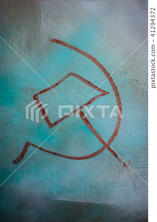 Red hammer and sickle painted on a blue colored wall. Vertical orientation 41294372
