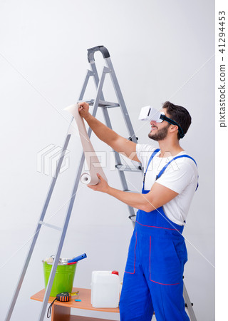 Man with VR glasses gluing wallpaper 41294453