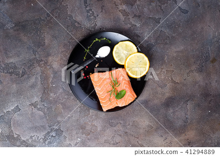 Salmon steaks on ice with lemon and salt on black plate. Lean proteins. 41294889