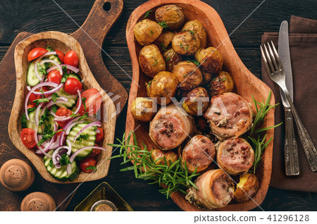 Baked pork medalions in bacon with potatoes. Baked pork medalions in bacon with potatoes. 41296128