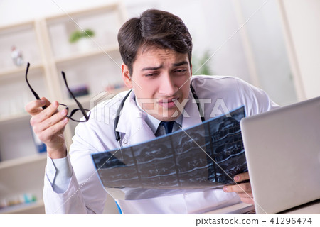 Young doctor looking at x-ray images in clinic Young doctor looking at x-ray images in clinic 41296474