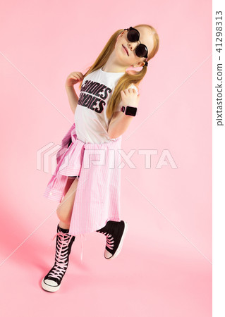 Girl with red tails on a pink background. A charming girl in bright sports clothes and sunglasses Girl with red tails on a pink background. A charming girl in bright sports clothes and sunglasses 41298313