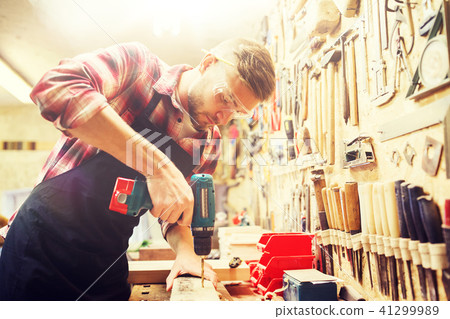 carpenter with drill drilling plank at workshop carpenter with drill drilling plank at workshop 41299989