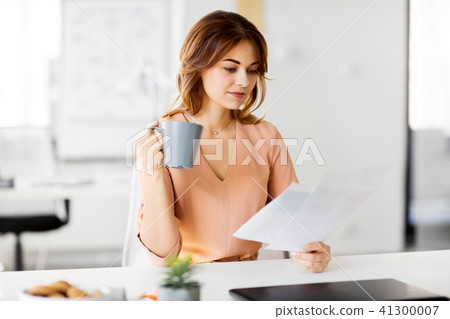 businesswoman with papers drinks coffee at office 41300007