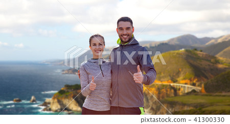 smiling couple in sport clothes showing thumbs up 41300330