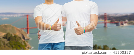 gay couple with rainbow wristbands shows thumbs up 41300337