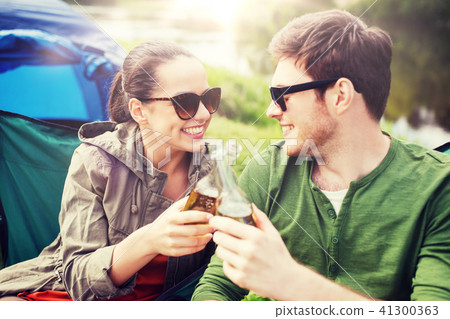 happy couple clinking drinks at campsite tent 41300363