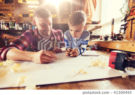 happy father and son with blueprint at workshop 41300493