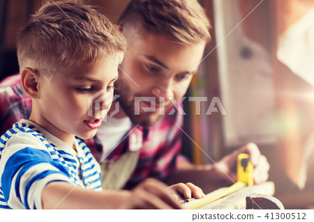 father and son with ruler measure wood at workshop 41300512