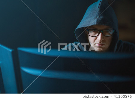 close up of hacker in hood at computer monitor 41300576