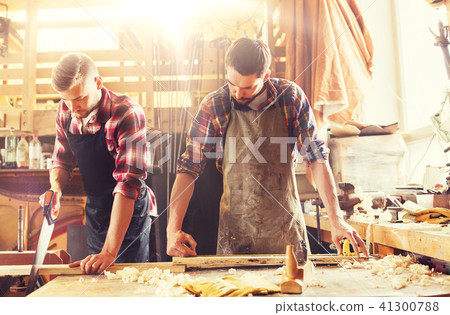 carpenters working with saw and wood at workshop carpenters working with saw and wood at workshop 41300788