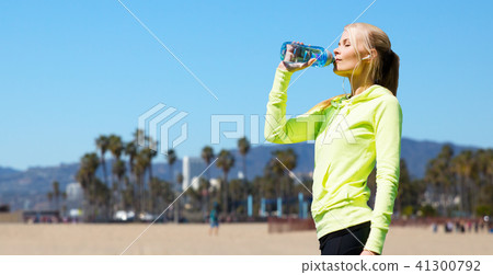 woman drinking water after doing sports outdoors 41300792