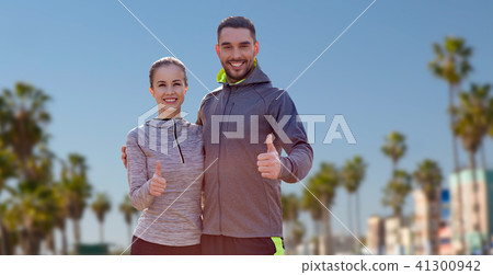 smiling couple in sport clothes showing thumbs up 41300942