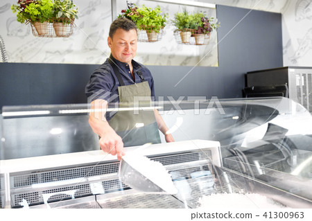 male seller adding ice to fridge at grocery store male seller adding ice to fridge at grocery store 41300963